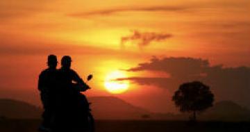 Thumbnail image of two people on a motorcycle at sunset