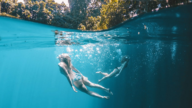 females swimming in a blue water hole