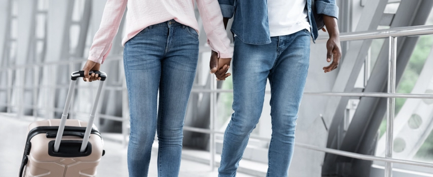 Couple walking through airport pulling suitcases