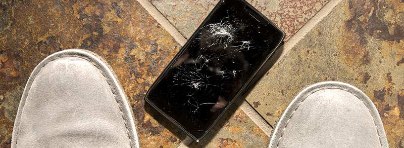 Dropped phone with smashed screen between owner's shoes
