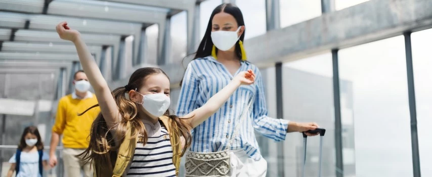 Family going on holiday at airport wearing face masks