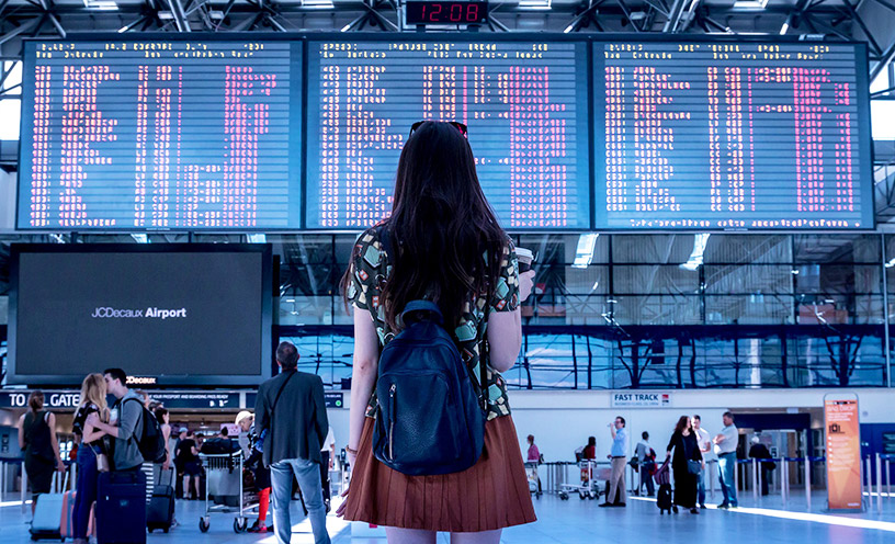 woman at airport looking at flight schedule