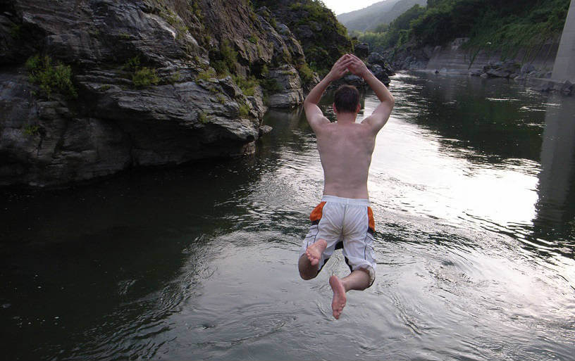 Man jumping off rock into water at Nagatoro, Japan