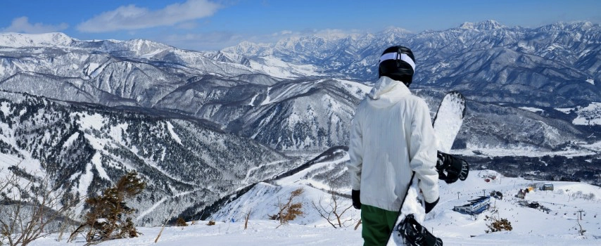 Snowboarder holding board looking at mountains