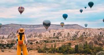 Woman admiring hot air balloons in Turkey on a well-planned holiday