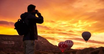 Man taking a photo of hot air balloons at sunrise in Turkey