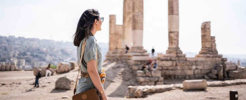 Woman who purchased travel insurance looks at ruins in Jordan