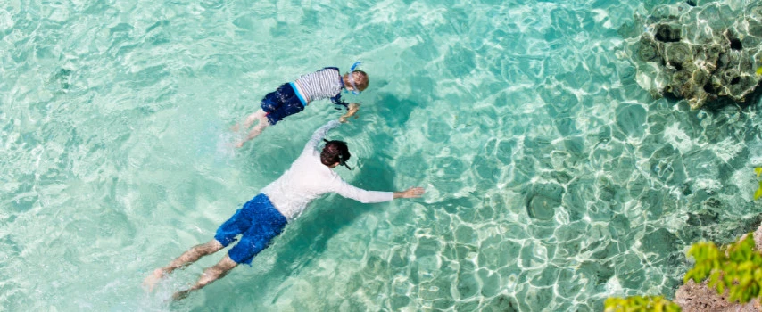 Father and son, who purchased travel insurance before their trip, go snorkeling while on holiday